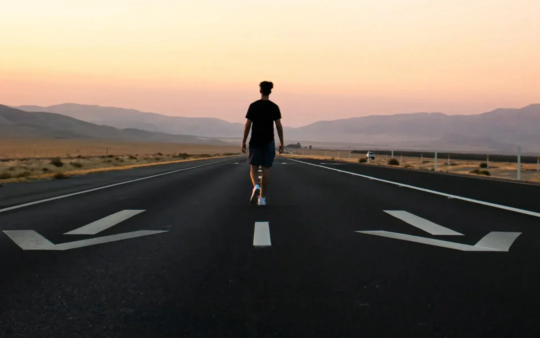 Man on highway walking opposite of directional arrows